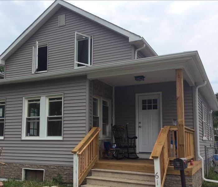 House repaired with new porch and new gray siding