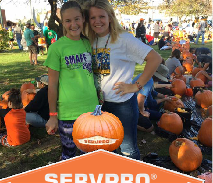 Two girls posing in front of the Marine City Area Chambers pumpkin carving contest.